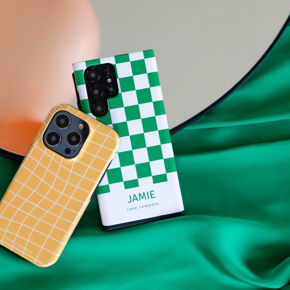 To robuste covers: et gult ternet cover til iPhone og et grønt skakternet cover med navnet Jamie